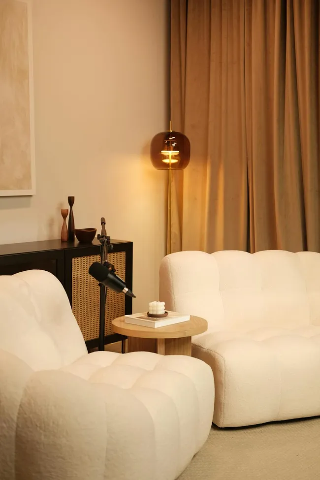 Twee crèmekleurige bouclé fauteuils in een sfeervolle woonkamer met warm licht